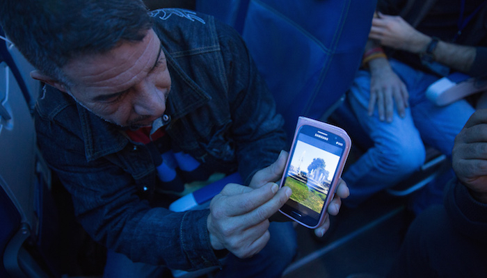 A Syrian refugee shows his home town of Hama on his phone while enroute to Canada. © IOM/Muse Mohammed 2015