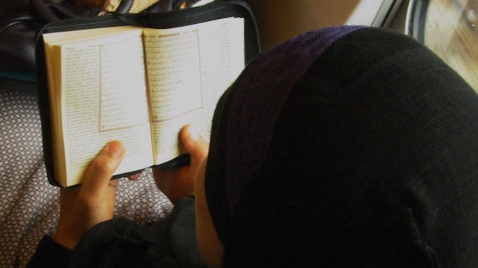 Moslima leest in de Koran. Trein bij vertrek in Leuven. Door Steven Hiawatha, via Flickr.